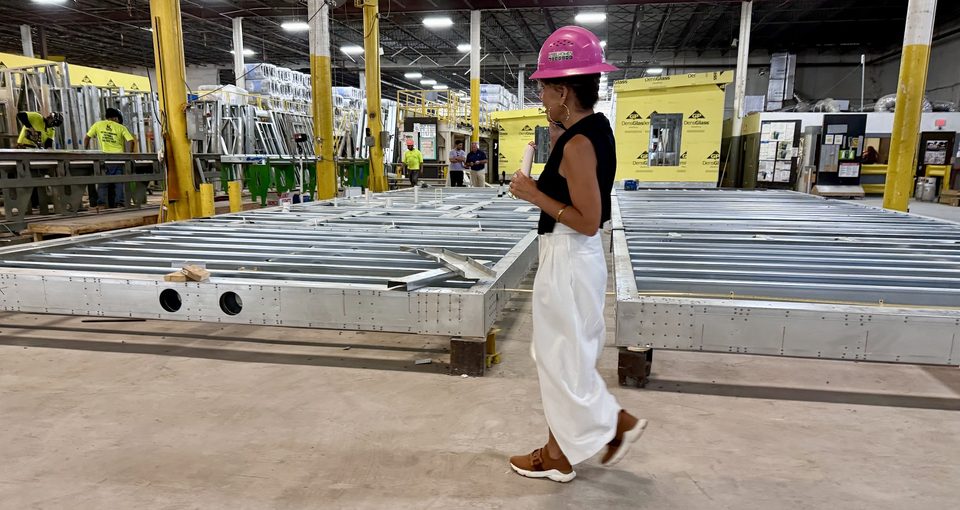 Antoinette Emanuel in a pink Steel Homes hard hat on the factory floor